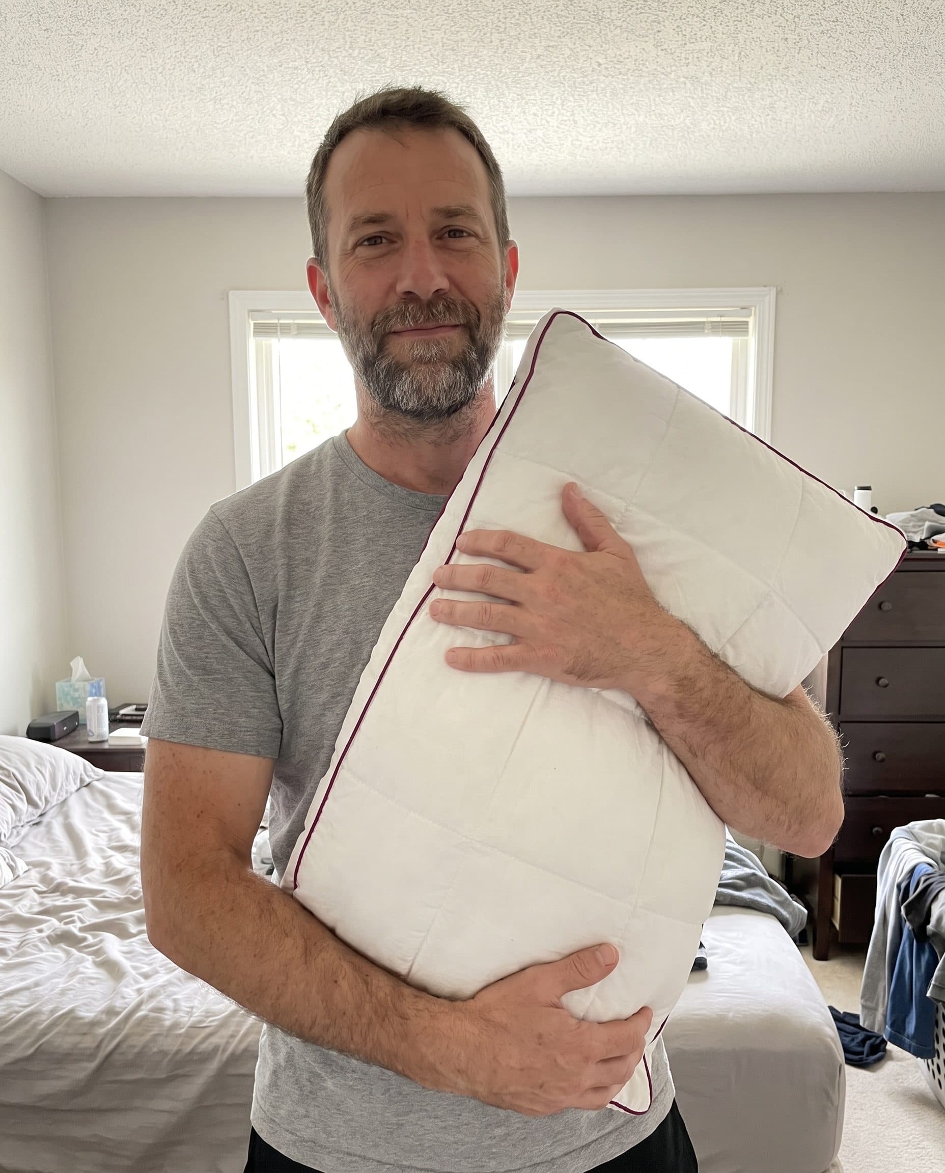 A man holding the Miyora pillow in his bedroom